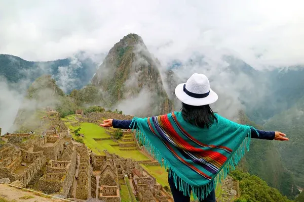 Una mujer de espaldas admirando la ciudadela de Machu Picchu en Perú